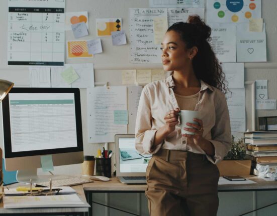 A worker drinks out of a mug in an office.