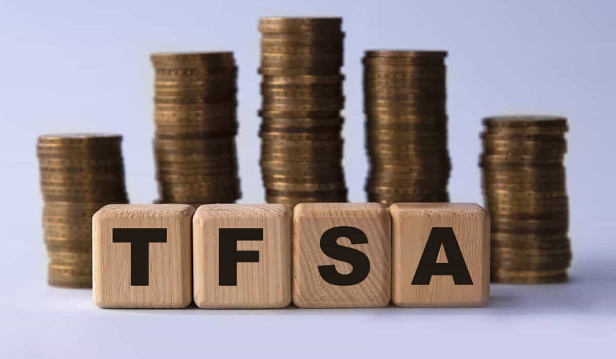 TFSA (Tax free savings account) acronym on wooden cubes on the background of stacks of coins