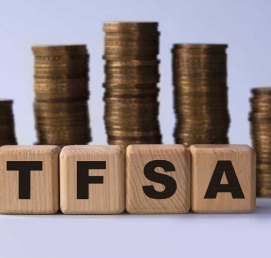 TFSA (Tax free savings account) acronym on wooden cubes on the background of stacks of coins