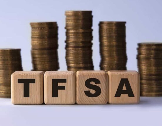 TFSA (Tax free savings account) acronym on wooden cubes on the background of stacks of coins
