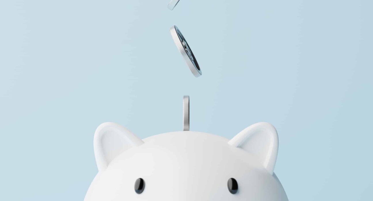 Silver coins fall into a piggy bank.