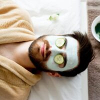 sleeping man relaxes with clay mask and cucumbers on eyes