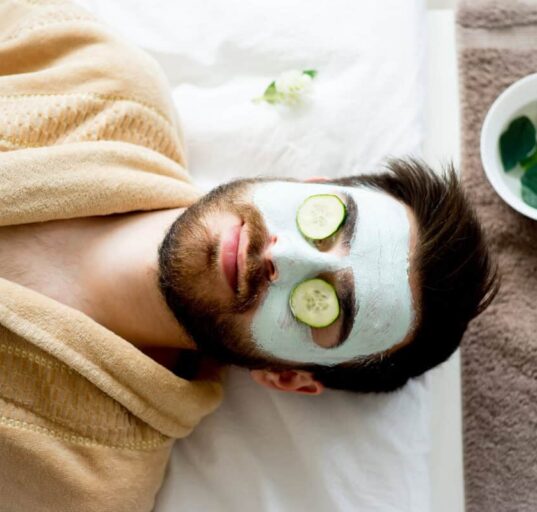 sleeping man relaxes with clay mask and cucumbers on eyes