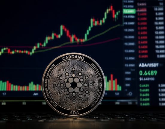 Cardano ADA coin stands in front of a trading screen showing a rising crypto price chart.
