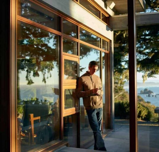 person on phone leaning against outside wall with scenic view at airbnb rental property