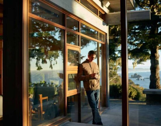 person on phone leaning against outside wall with scenic view at airbnb rental property
